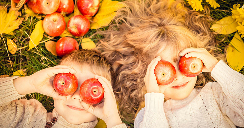 Дети с яблоками в руках на фоне глаз